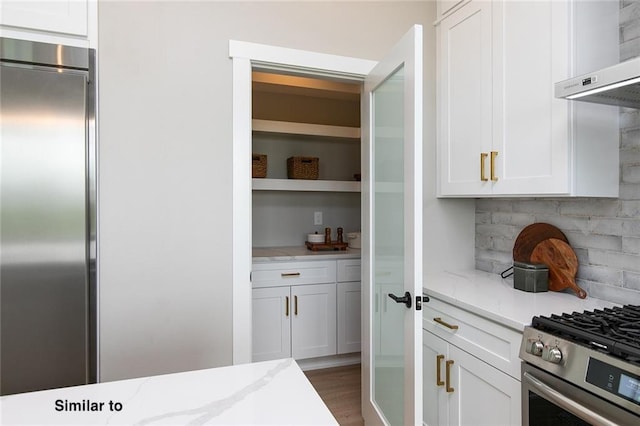 790 Hamilton Rd, Waukee, IA 50263 - kitchen with wall chimney range hood, stainless steel appliances, white cabinetry, and light stone counters