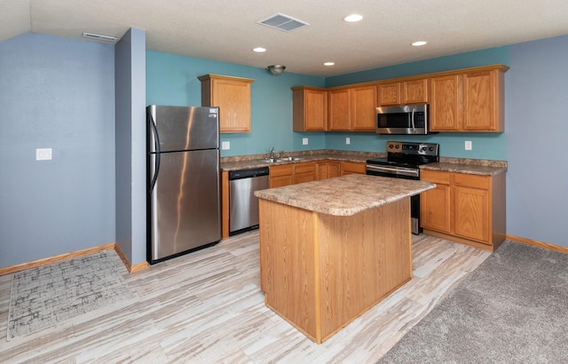 1115 Fieldstone Ln, Pleasant Hill, IA 50327 - kitchen with appliances with stainless steel finishes, light wood-type flooring, a kitchen island, recessed lighting, and brown cabinetry