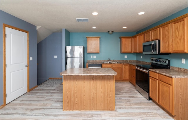 1115 Fieldstone Ln, Pleasant Hill, IA 50327 - kitchen featuring appliances with stainless steel finishes, a center island, light wood-style floors, recessed lighting, and a textured ceiling