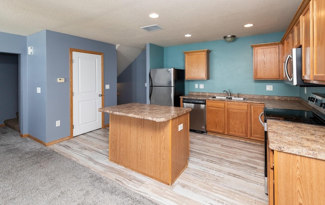1115 Fieldstone Ln, Pleasant Hill, IA 50327 - kitchen with stainless steel appliances, a kitchen island, a textured ceiling, light wood-style floors, and recessed lighting