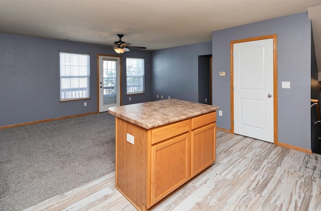 1115 Fieldstone Ln, Pleasant Hill, IA 50327 - kitchen with a ceiling fan, light countertops, a center island, light wood-style floors, and open floor plan