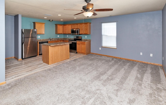1115 Fieldstone Ln, Pleasant Hill, IA 50327 - kitchen with stainless steel appliances, a kitchen island, a ceiling fan, light colored carpet, and recessed lighting