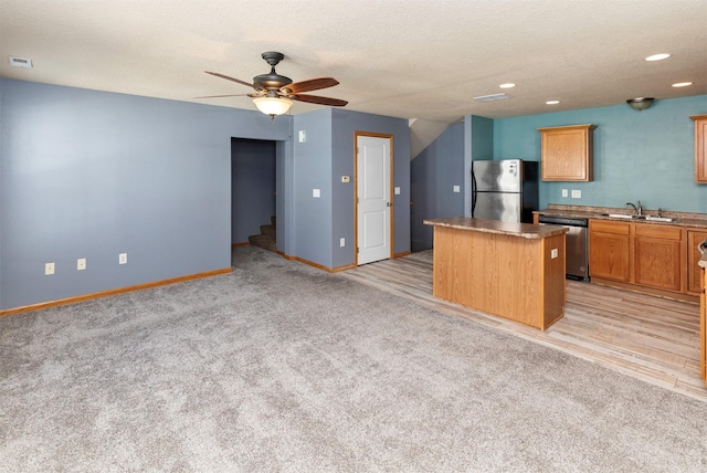 1115 Fieldstone Ln, Pleasant Hill, IA 50327 - kitchen featuring appliances with stainless steel finishes, a kitchen island, light carpet, a ceiling fan, and recessed lighting