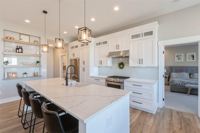 17965 Hammontree Cir, Clive, IA 50325 - kitchen with under cabinet range hood, stainless steel appliances, a kitchen island with sink, open shelves, and white cabinetry