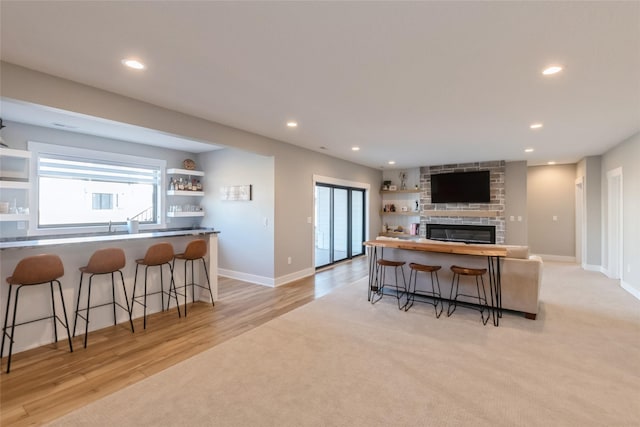 17965 Hammontree Cir, Clive, IA 50325 - kitchen featuring a breakfast bar area, open shelves, recessed lighting, light wood-style flooring, and a fireplace