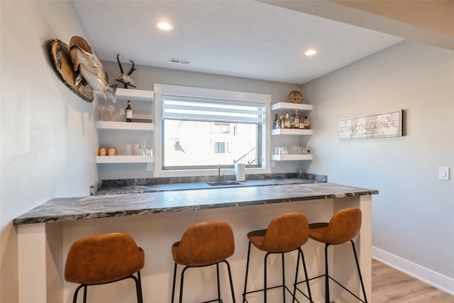 17965 Hammontree Cir, Clive, IA 50325 - kitchen with open shelves, light wood-style flooring, a kitchen breakfast bar, recessed lighting, and a peninsula