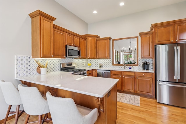 3607 152nd St, Urbandale, IA 50323 - kitchen with appliances with stainless steel finishes, a peninsula, a breakfast bar, light countertops, and brown cabinetry