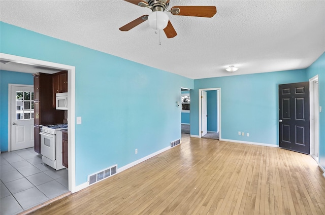 217 E Park Ave, Des Moines, IA 50315 - unfurnished living room featuring ceiling fan, light wood-type flooring, and a textured ceiling
