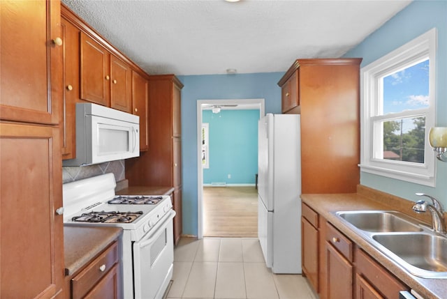 217 E Park Ave, Des Moines, IA 50315 - kitchen with white appliances, light tile patterned floors, brown cabinetry, tasteful backsplash, and a textured ceiling