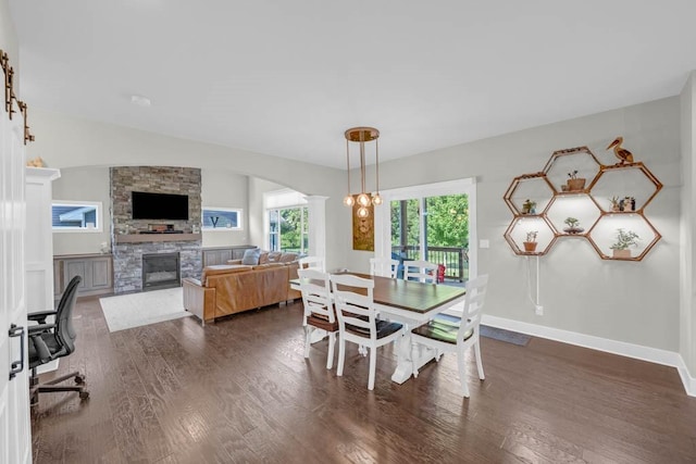 1965 SE Waddell Way, Waukee, IA 50263 - dining space featuring dark wood-style flooring, a fireplace, arched walkways, and decorative columns