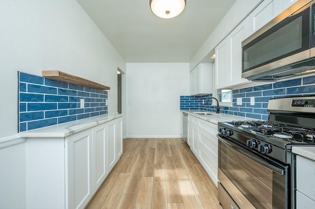 1205 Elder Ln, Des Moines, IA 50315 - kitchen with appliances with stainless steel finishes, backsplash, light wood-style flooring, white cabinetry, and light stone countertops