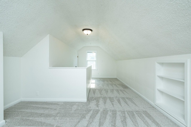 1205 Elder Ln, Des Moines, IA 50315 - bonus room with a textured ceiling, carpet flooring, vaulted ceiling, and built in shelves