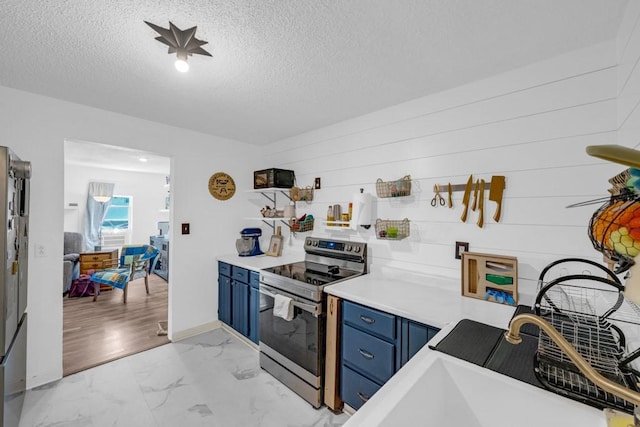 1020 SW 3rd St, Nevada, IA 50201 - kitchen featuring blue cabinetry, electric stove, light marble finish floors, a textured ceiling, and light countertops