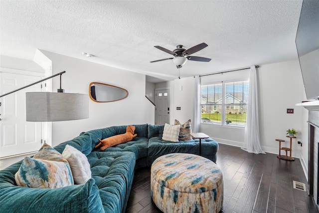 3504 Hawthorn Dr SW, Bondurant, IA 50035 - living room featuring a textured ceiling, dark wood-type flooring, a ceiling fan, and a fireplace