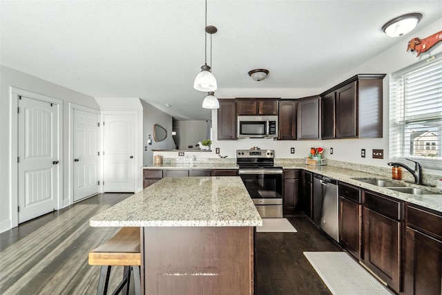 3504 Hawthorn Dr SW, Bondurant, IA 50035 - kitchen with appliances with stainless steel finishes, a kitchen island, dark wood-type flooring, dark brown cabinetry, and light stone counters