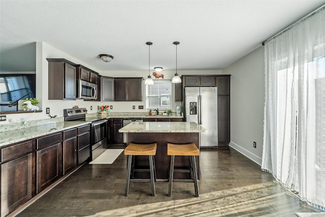 3504 Hawthorn Dr SW, Bondurant, IA 50035 - kitchen featuring stainless steel appliances, dark brown cabinetry, a kitchen island, and light stone counters