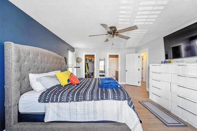 3504 Hawthorn Dr SW, Bondurant, IA 50035 - bedroom featuring wood finished floors, a walk in closet, ceiling fan, and a textured ceiling