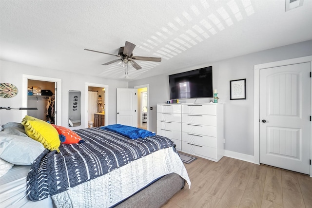 3504 Hawthorn Dr SW, Bondurant, IA 50035 - bedroom with wood finished floors, ceiling fan, a walk in closet, ensuite bathroom, and a textured ceiling