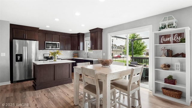 1208 NE 21st St, Grimes, IA 50111 - kitchen with stainless steel appliances, dark brown cabinetry, light countertops, backsplash, and light wood-style flooring