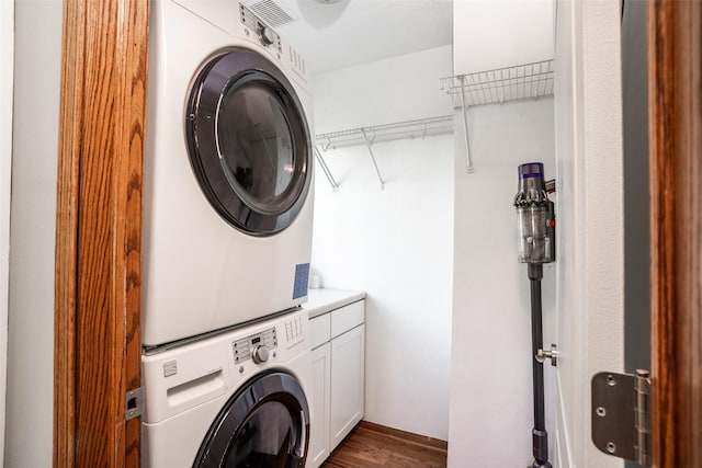 4785 Windsor Cir, Pleasant Hill, IA 50327 - washroom featuring stacked washer and clothes dryer, cabinet space, and dark wood-type flooring
