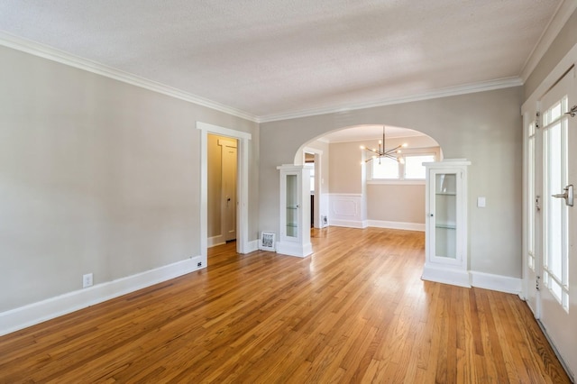 849 39th St, Des Moines, IA 50312 - spare room with arched walkways, a chandelier, light wood-style flooring, ornamental molding, and a textured ceiling