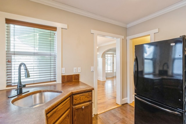 849 39th St, Des Moines, IA 50312 - kitchen with freestanding refrigerator, arched walkways, ornamental molding, brown cabinets, and light wood-style flooring
