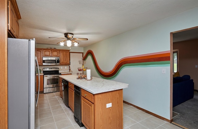 1612 Horse N Buggy Dr, Adel, IA 50003 - kitchen with appliances with stainless steel finishes, a center island, light countertops, ceiling fan, and brown cabinets