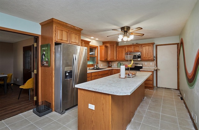 1612 Horse N Buggy Dr, Adel, IA 50003 - kitchen with appliances with stainless steel finishes, light countertops, brown cabinets, a kitchen island, and ceiling fan