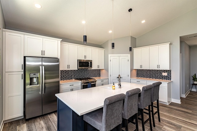 409 S St, Jewell, IA 50130 - kitchen with appliances with stainless steel finishes, lofted ceiling, backsplash, an island with sink, and light countertops