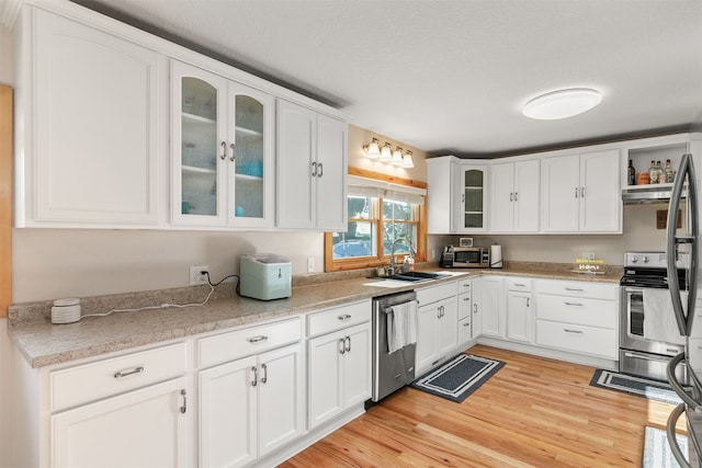 122 G76 Hwy, Lacona, IA 50139 - kitchen featuring appliances with stainless steel finishes, light wood-style flooring, white cabinetry, light countertops, and glass insert cabinets