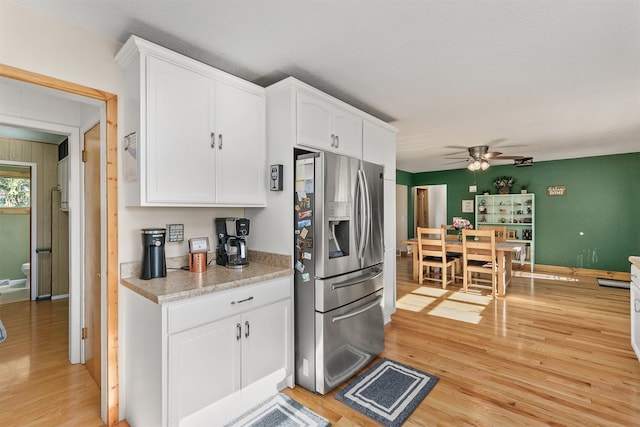 122 G76 Hwy, Lacona, IA 50139 - kitchen with stainless steel refrigerator with ice dispenser, light wood-style flooring, a ceiling fan, and white cabinets