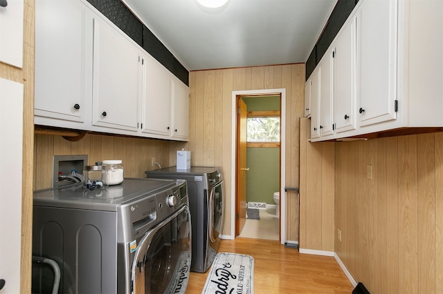 122 G76 Hwy, Lacona, IA 50139 - laundry area with cabinet space, washer and clothes dryer, light wood-style floors, and wood walls