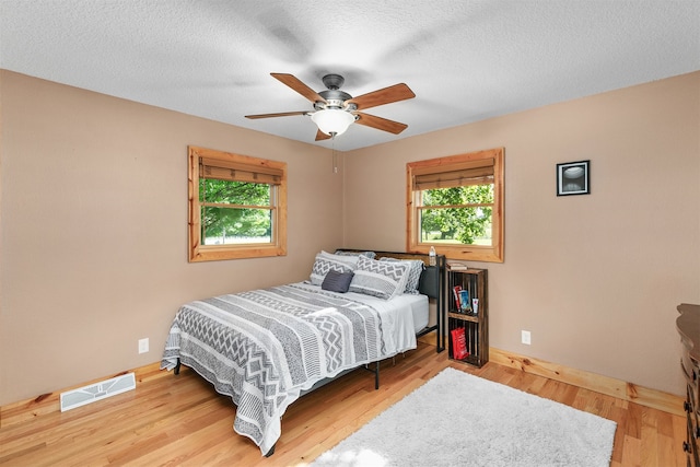 122 G76 Hwy, Lacona, IA 50139 - bedroom with multiple windows, wood finished floors, a ceiling fan, and a textured ceiling