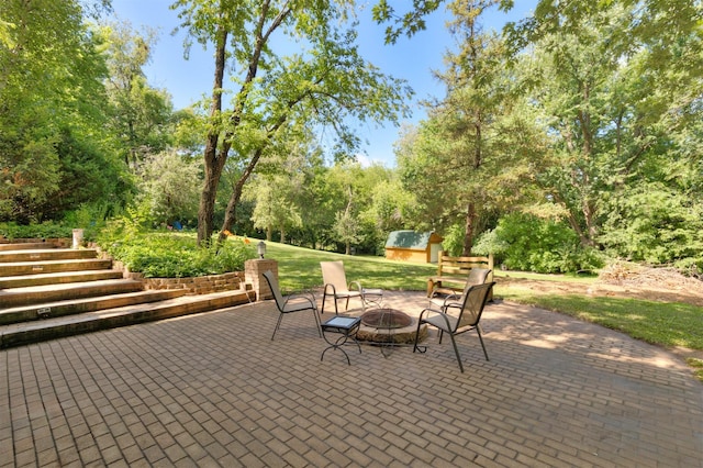 702 Jasper Ave NE, Mitchellville, IA 50169 - view of patio with a storage shed, a fire pit, and view of wooded area
