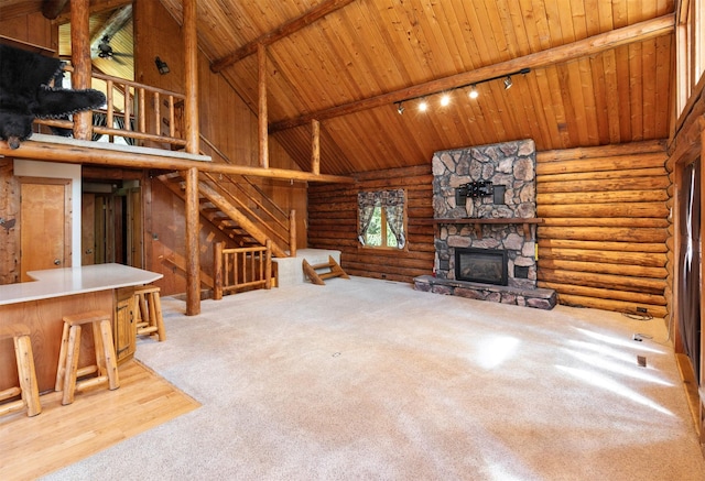 702 Jasper Ave NE, Mitchellville, IA 50169 - unfurnished living room with high vaulted ceiling, track lighting, a stone fireplace, rustic walls, and a wood ceiling with exposed beams