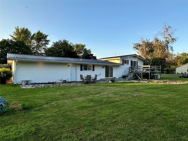 94 14th Ave, Grinnell, IA 50112 - rear view of property featuring a wooden deck, a lawn, and a metal roof