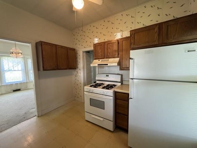 4046 4th St, Des Moines, IA 50313 - kitchen featuring white appliances, under cabinet range hood, light floors, ceiling fan, and a chandelier
