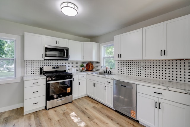 1437 E Pleasant View Dr, Des Moines, IA 50320 - kitchen featuring stainless steel appliances, white cabinetry, decorative backsplash, and light stone countertops