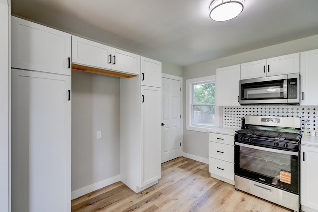 1437 E Pleasant View Dr, Des Moines, IA 50320 - kitchen featuring stainless steel appliances, light wood-type flooring, white cabinets, decorative backsplash, and light stone counters