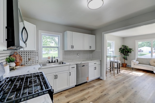 1437 E Pleasant View Dr, Des Moines, IA 50320 - kitchen featuring stainless steel dishwasher, gas range, decorative backsplash, and white cabinetry