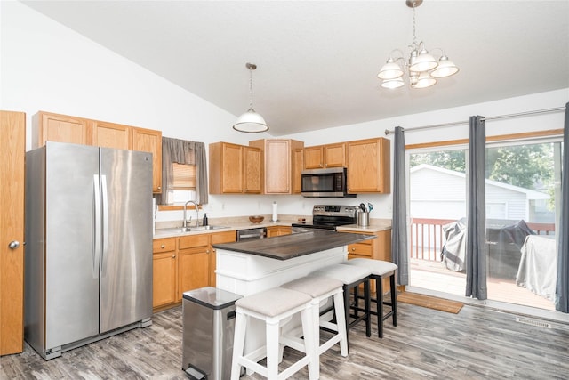 6217 Welker Ave, Des Moines, IA 50312 - kitchen featuring appliances with stainless steel finishes, a chandelier, light wood-style floors, a breakfast bar area, and hanging light fixtures