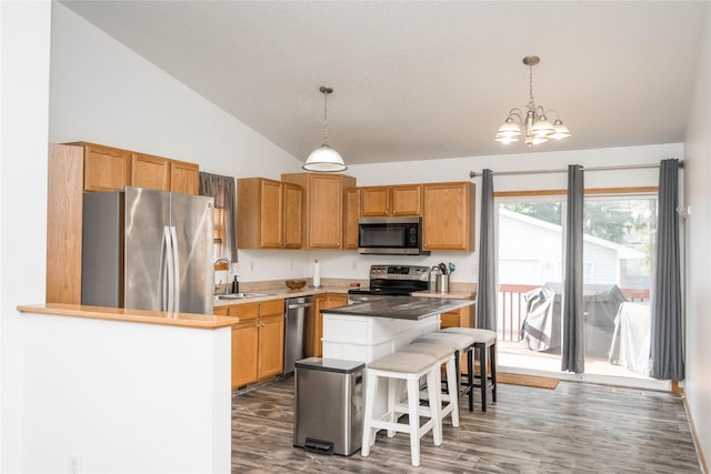6217 Welker Ave, Des Moines, IA 50312 - kitchen with stainless steel appliances, a kitchen breakfast bar, vaulted ceiling, a chandelier, and hanging light fixtures