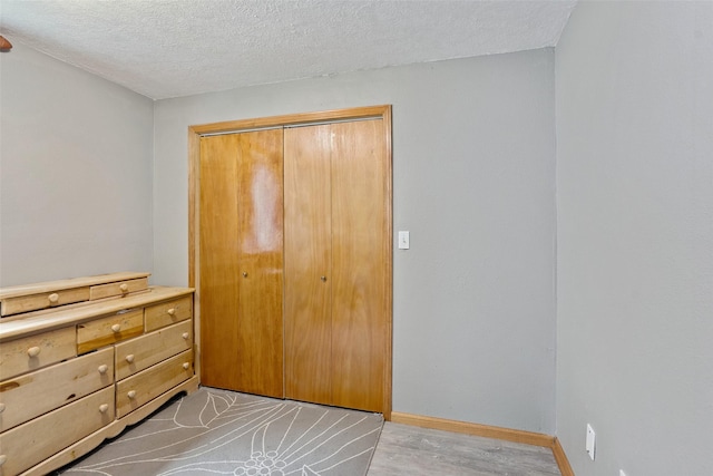 221 E Payton Ave, Des Moines, IA 50315 - bedroom featuring a textured ceiling, a closet, and light wood-style flooring