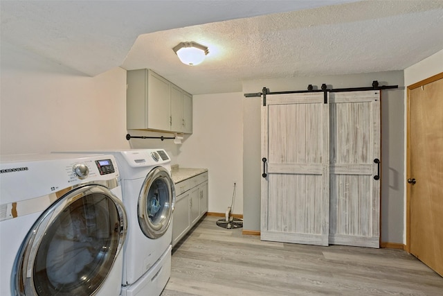 221 E Payton Ave, Des Moines, IA 50315 - laundry area with washing machine and clothes dryer, a barn door, light wood-style floors, cabinet space, and a textured ceiling