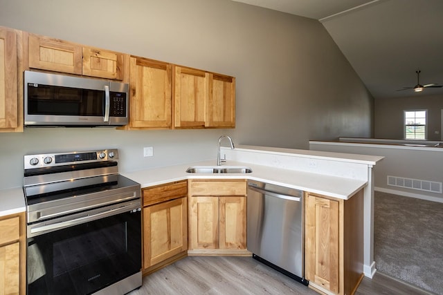 1102 Westview Dr, Huxley, IA 50124 - kitchen featuring appliances with stainless steel finishes, lofted ceiling, a peninsula, light wood-type flooring, and light countertops
