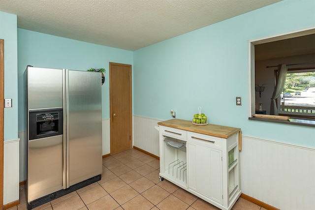 2525 27th Pl, Des Moines, IA 50310 - kitchen with stainless steel fridge, a wainscoted wall, white cabinets, butcher block countertops, and light tile patterned flooring