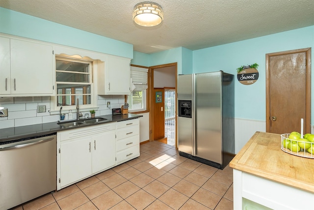 2525 27th Pl, Des Moines, IA 50310 - kitchen featuring appliances with stainless steel finishes, white cabinetry, tasteful backsplash, dark countertops, and a textured ceiling