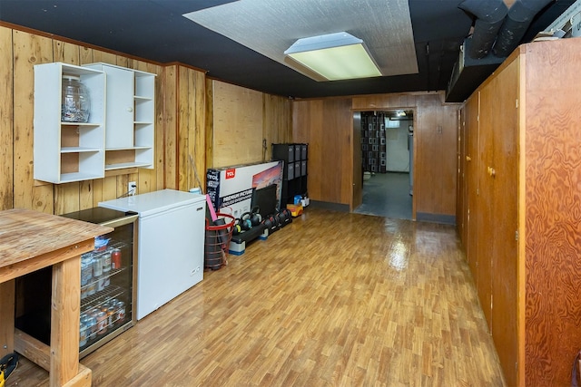 2525 27th Pl, Des Moines, IA 50310 - finished basement with wood walls, fridge, and light wood-style flooring