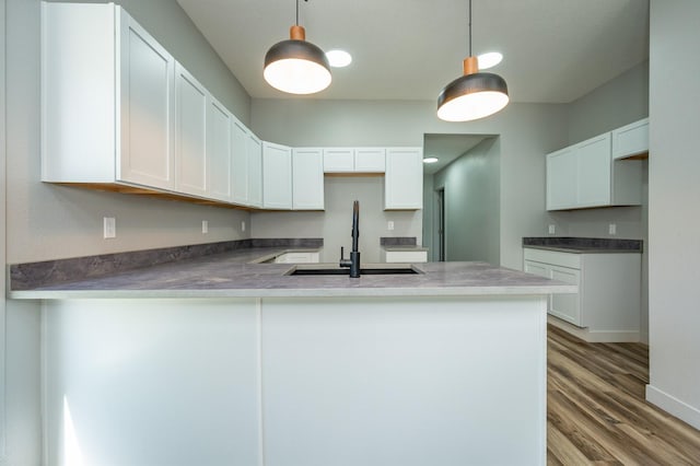611 W 2nd St S, Newton, IA 50208 - kitchen featuring a peninsula, wood finished floors, white cabinets, and pendant lighting