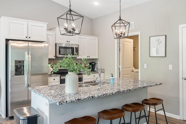 4315 E 48th St, Des Moines, IA 50317 - kitchen with stainless steel appliances, a chandelier, wood finished floors, white cabinetry, and lofted ceiling